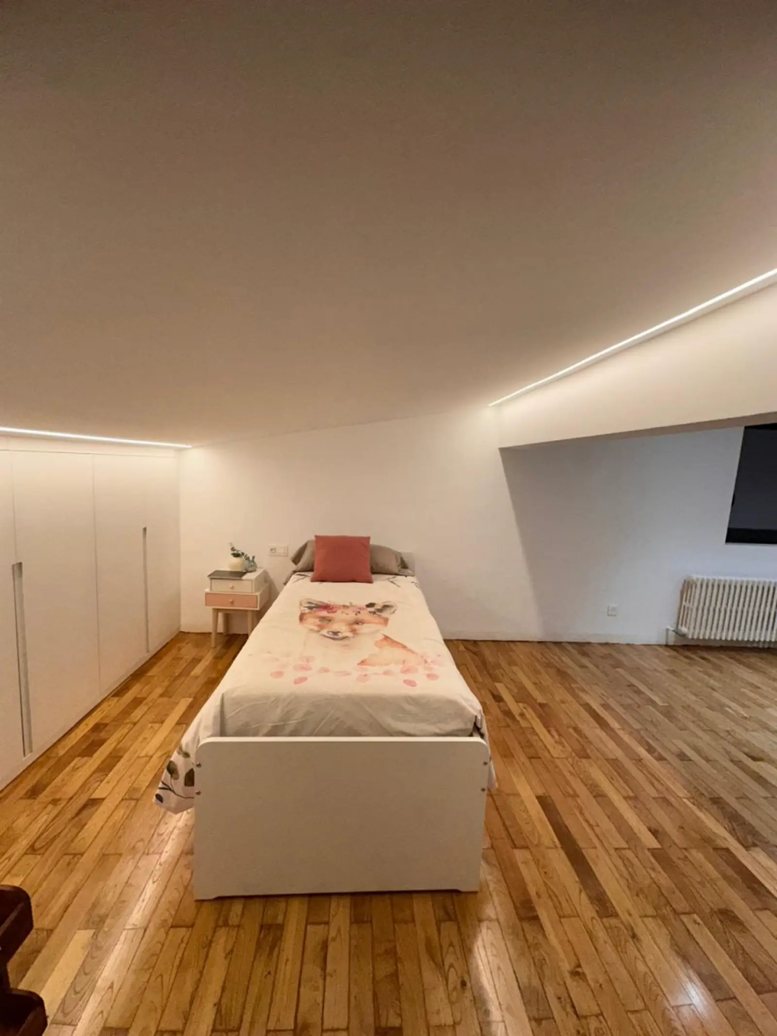 Buhardilla reformada como dormitorio con carpintería y suelo renovado